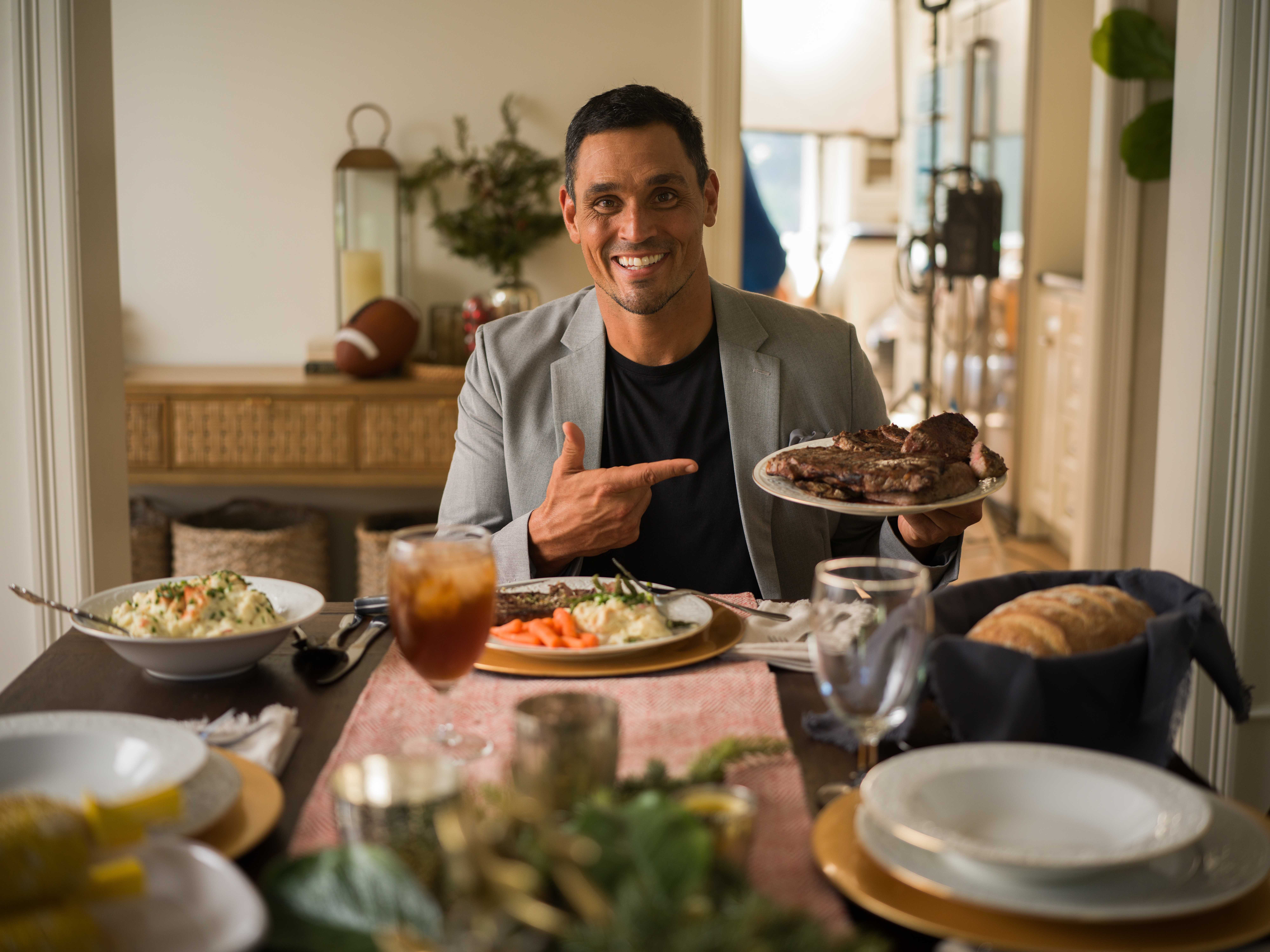 David Pollack — Dining room, dressed up at the table, presenting a steak.