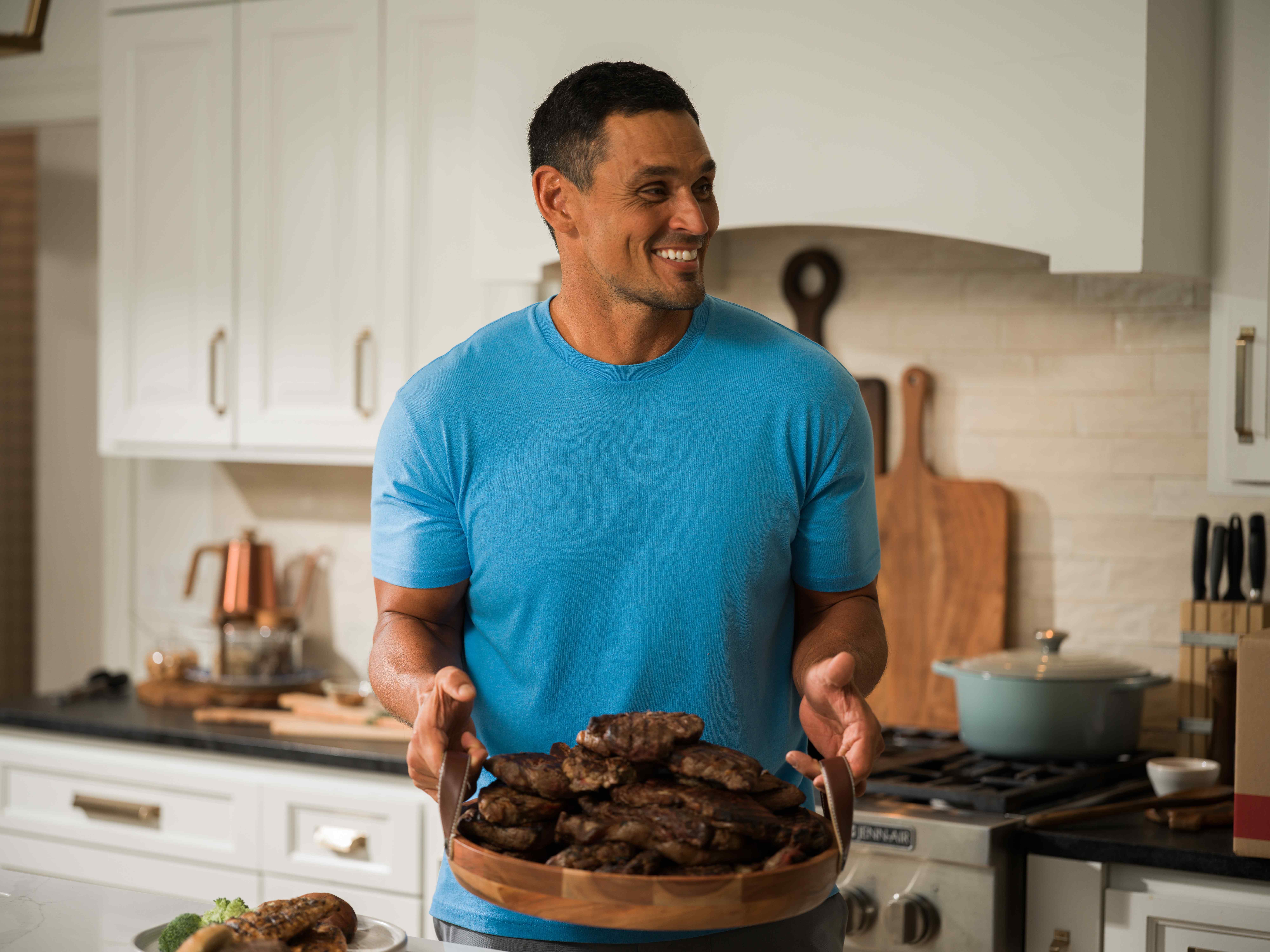 David Pollack — Kitchen, holding a platter of grilled steaks.