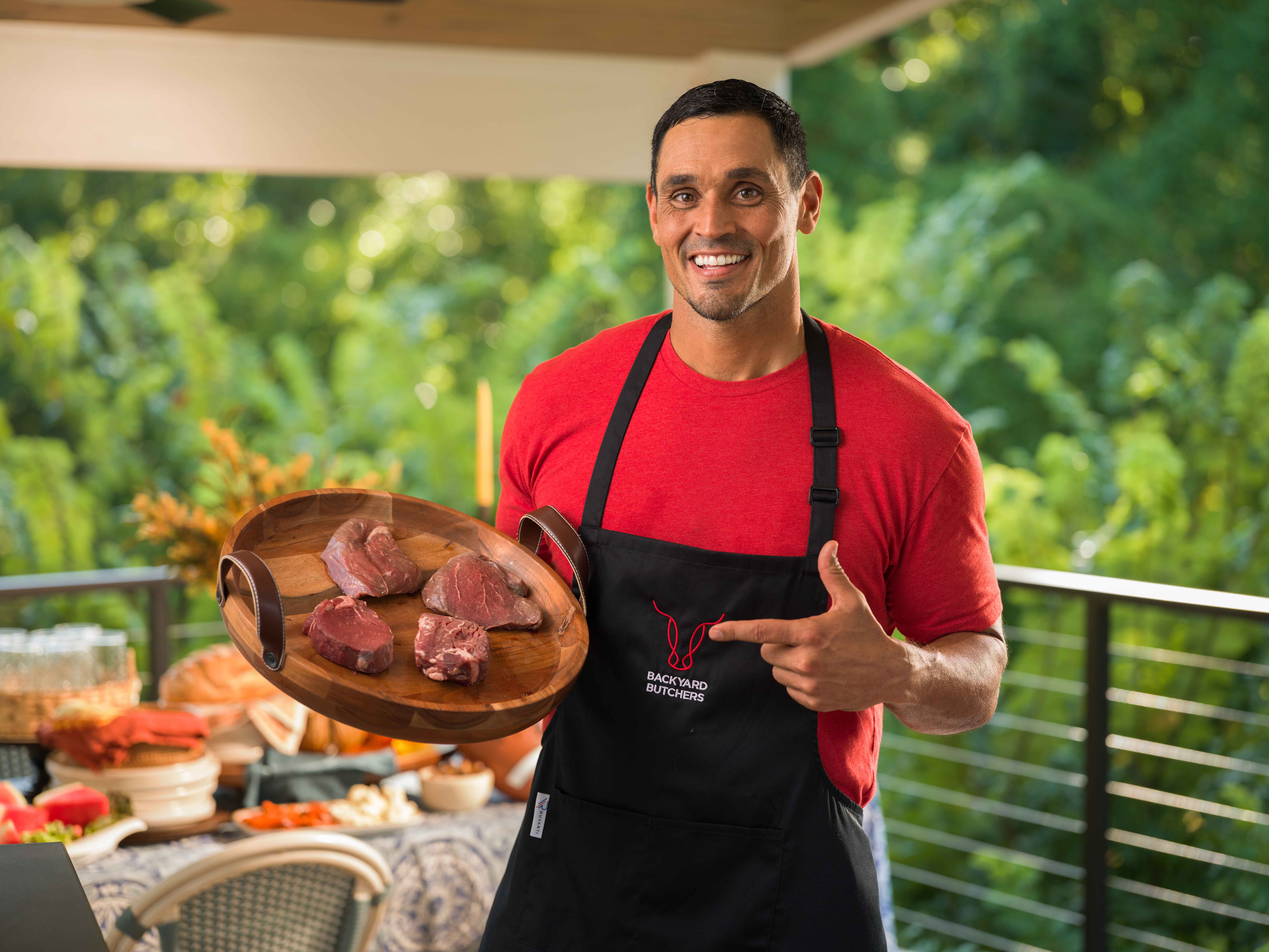 David Pollack — David on the patio, holding a board of raw steaks.