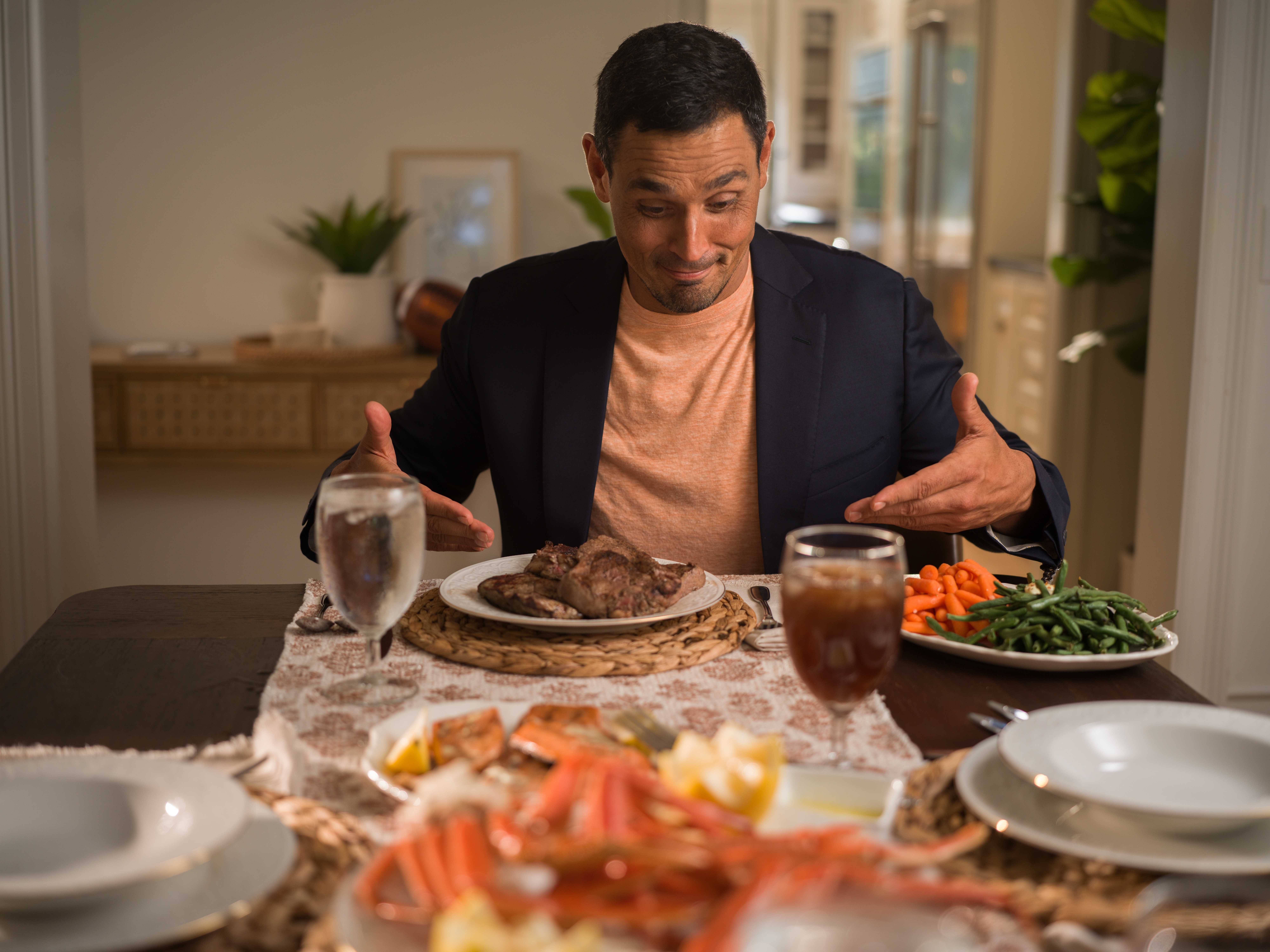 David at the dining table with steak, crab legs and sides.
